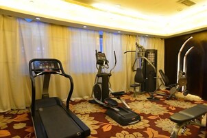 Gimnasio de hotel con cinta de correr, elíptica y máquina de pesas.