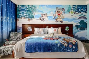 Un dormitorio con una cama grande, un cabecero con un mural navideño y una colcha azul.