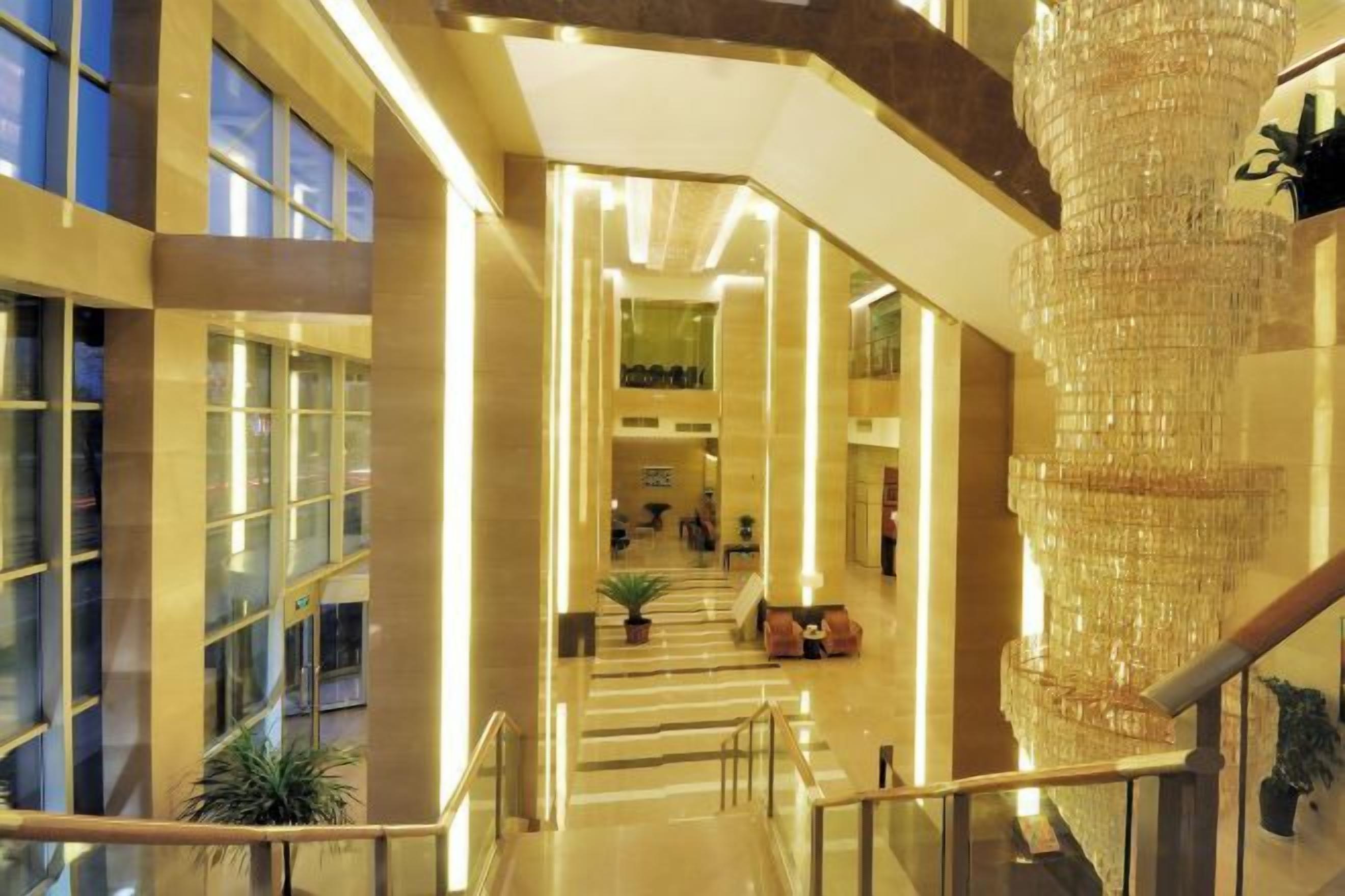 A spacious interior with a grand staircase, a large chandelier, and a view of the lobby area.