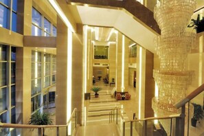 A spacious interior with a grand staircase, a large chandelier, and a view of the lobby area. - San Want Hotel (Xining)