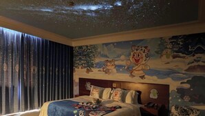A hotel room with a bed, a nightstand, a chair, and a mural on the wall depicting a snowy landscape with cartoon characters. - San Want Hotel (Xining)