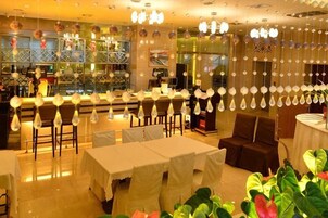 Un restaurante con mesas y sillas, lámparas colgantes y una zona de bar.
