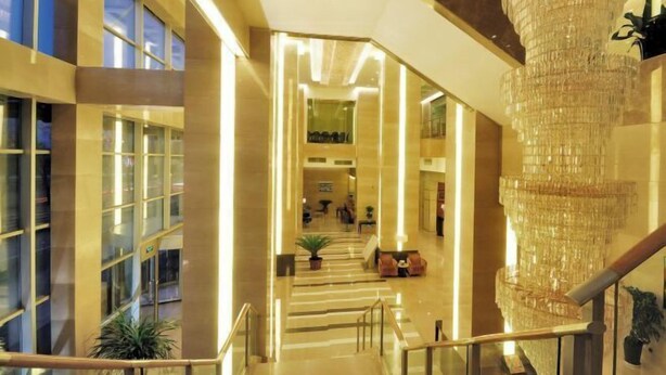 A modern hotel lobby with a grand staircase, a large chandelier, and a view of the interior space. - San Want Hotel (Xining)