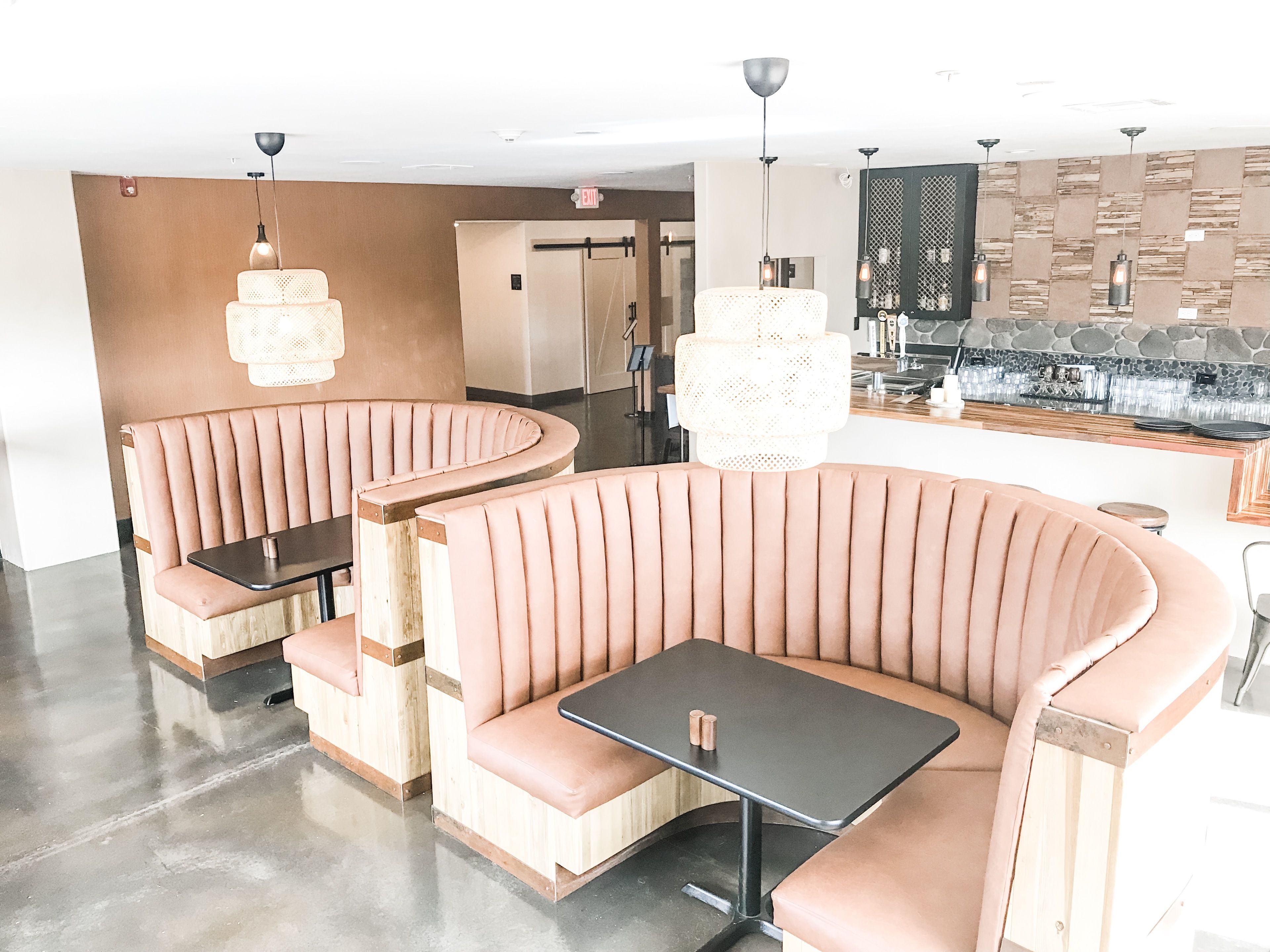 A modern restaurant with booth seating and a bar area.