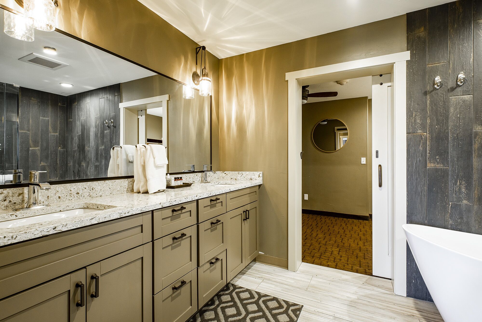 A modern bathroom with a large mirror, a bathtub, and a vanity with multiple drawers.