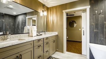 Un bany modern amb un mirall gran, una banyera i un lavabo amb múltiples calaixos.