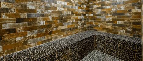 A bathroom with a stone wall and a pebble-patterned bench.