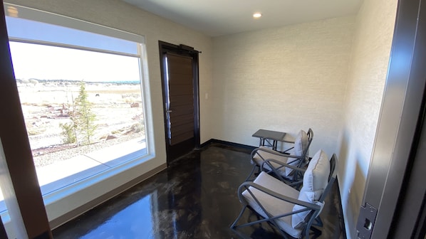 A room with a large window, a door, and a small table with chairs.