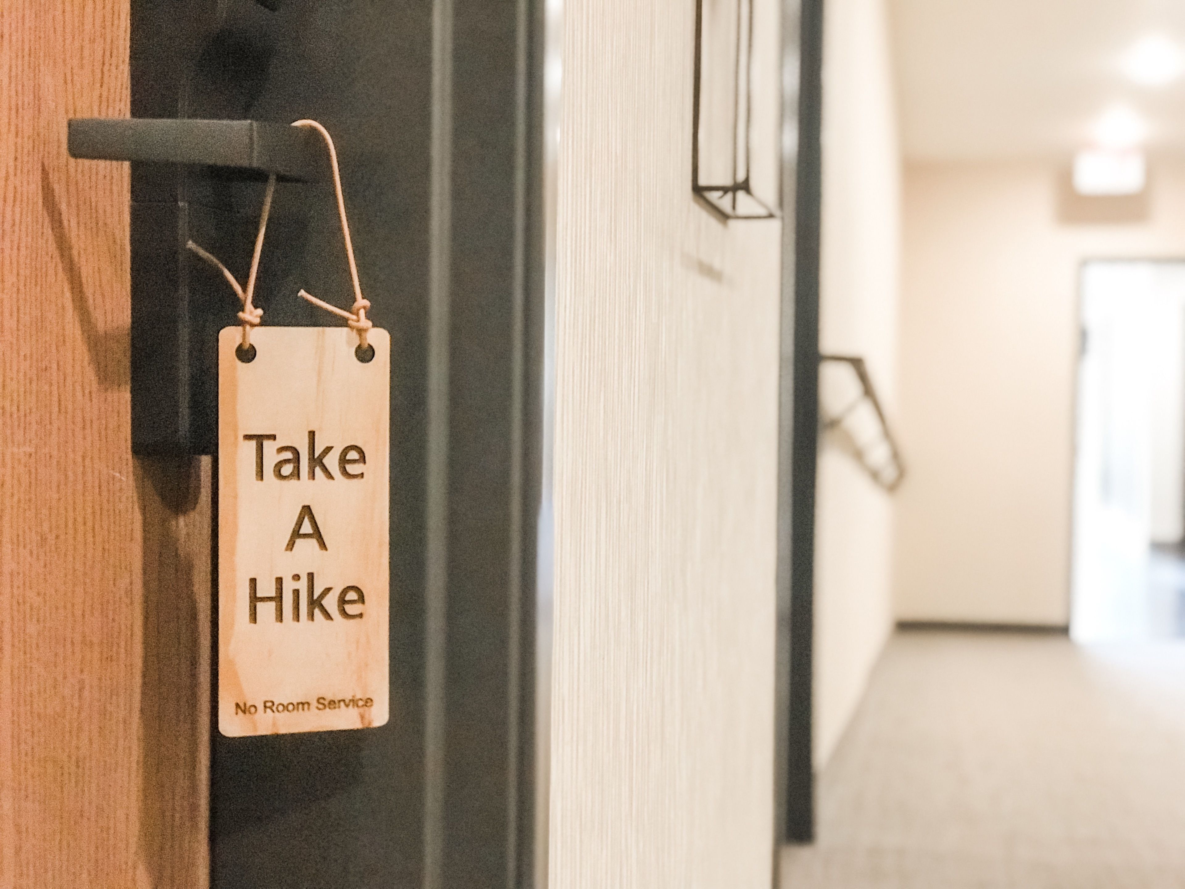 A sign on a door that reads "Take A Hike" and "No Room Service".
