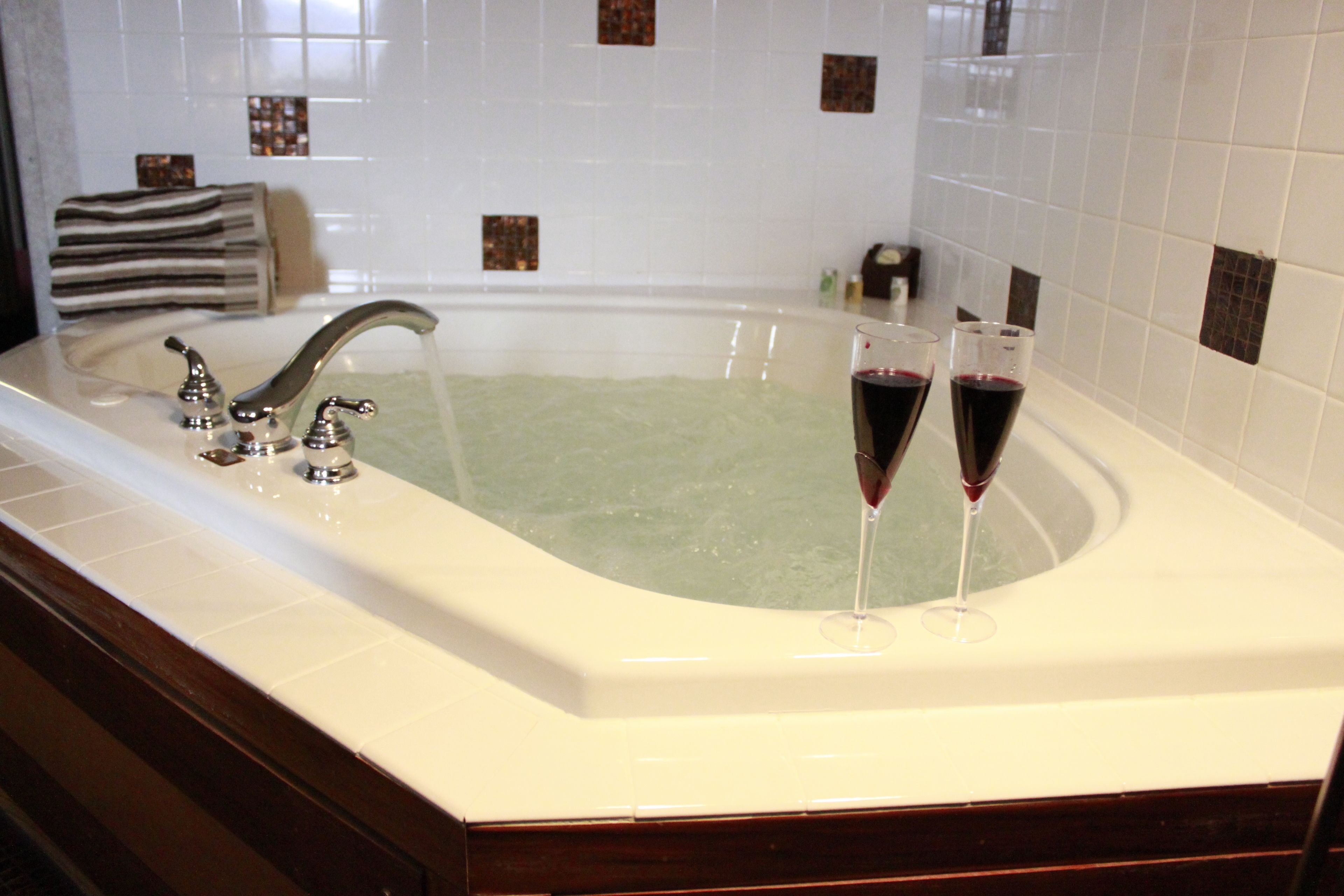 Una bañera grande con dos copas de vino tinto.