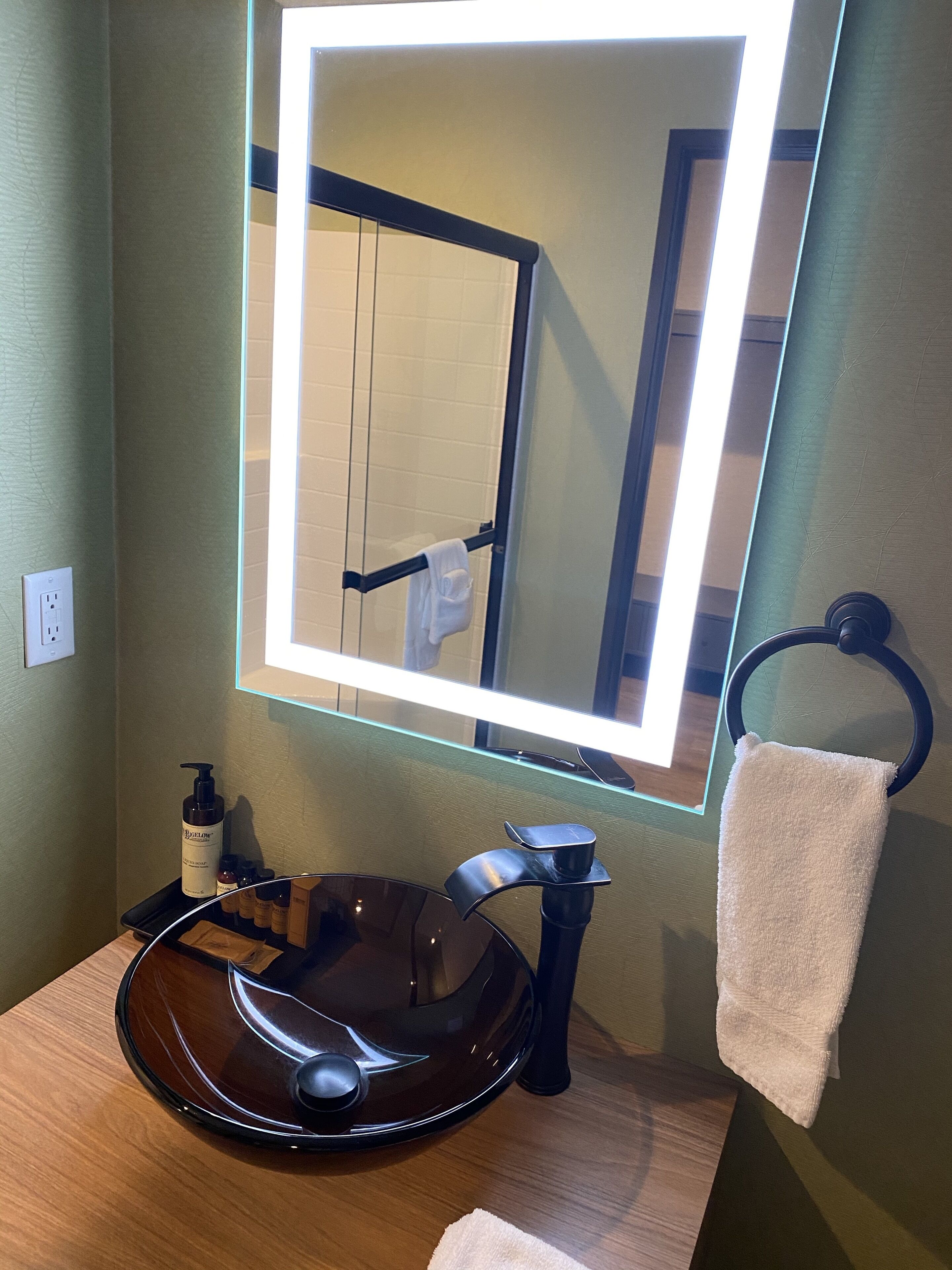 Une salle de bain avec un miroir rond, un lavabo et un porte-serviettes.