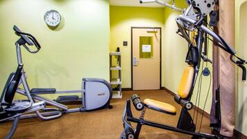 Un gimnasio con máquinas de cardio, un banco de pesas y un saco de boxeo.