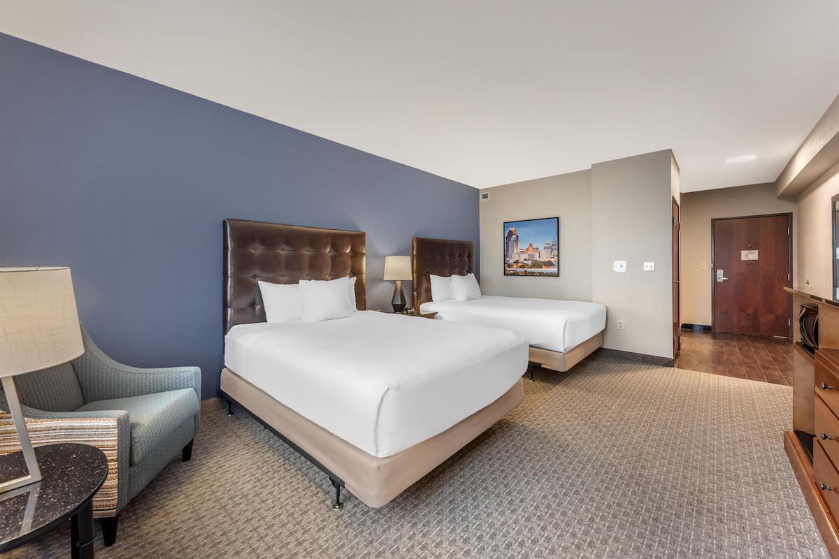 Une chambre d’hôtel avec deux lits, une chaise, une lampe et un tableau au mur.