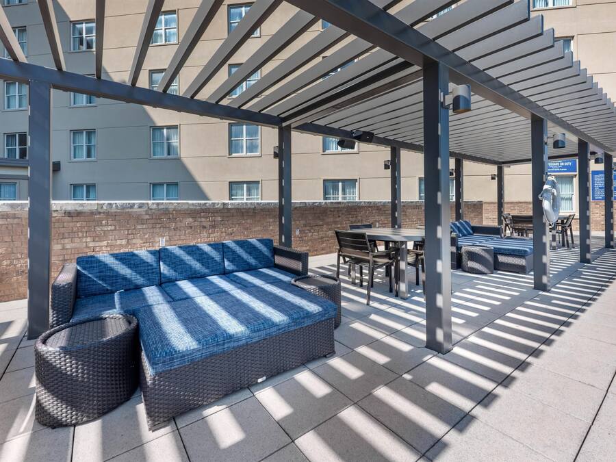 An outdoor seating area with a covered patio, a sofa, and a table with chairs.