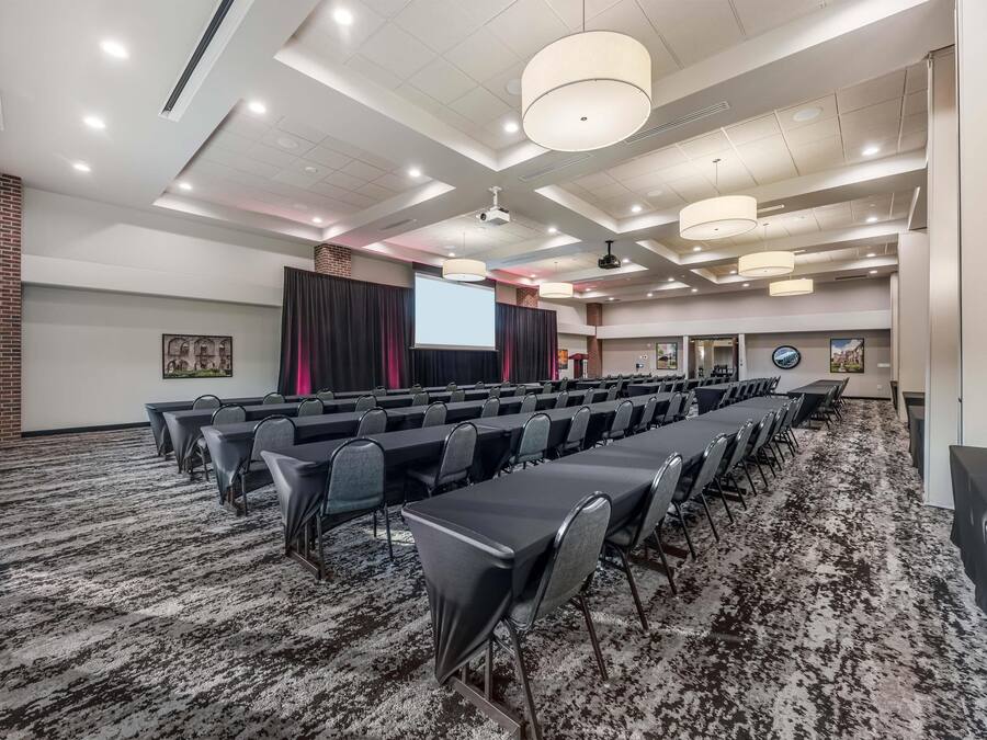 Un salón de conferencias con largas mesas, sillas y piso alfombrado.