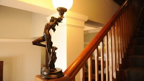 Un escalier avec une rampe en bois et une statue sur le palier.