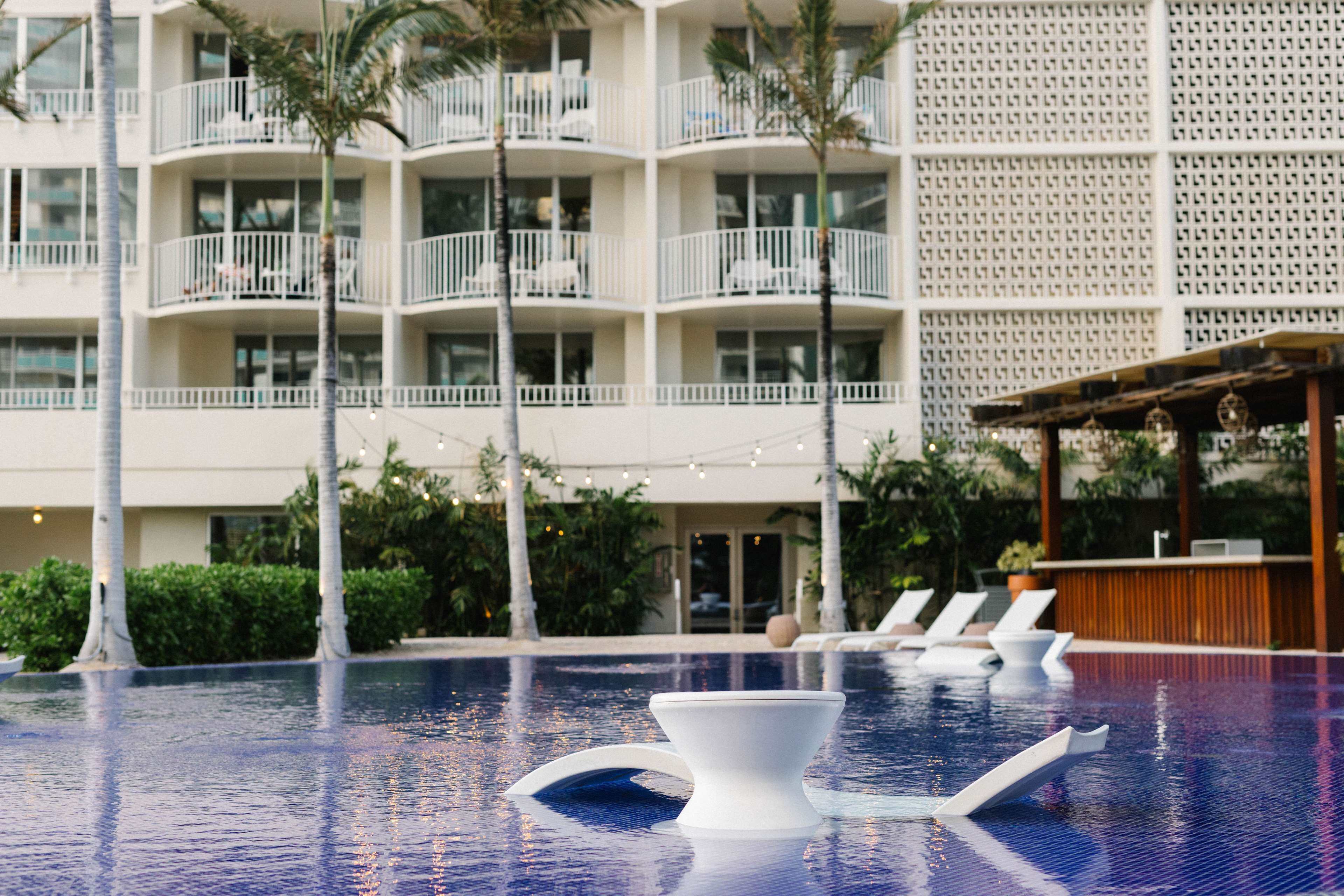 Un espace piscine d’hôtel avec des chaises longues et un bar.