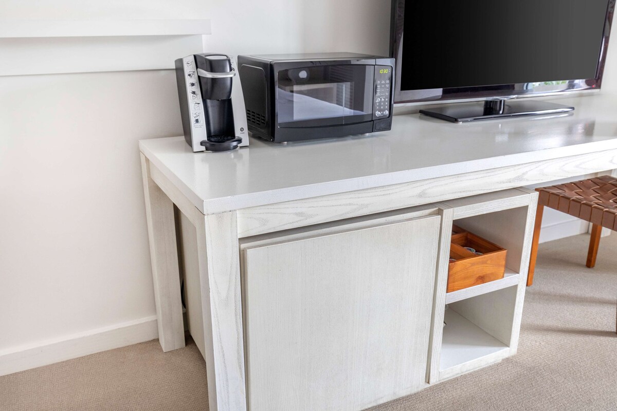 A white cabinet with a microwave and a coffee maker on top.