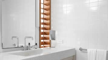 Un baño moderno con un espejo grande, dos lavamanos, un estante de madera y un perchero para toallas.