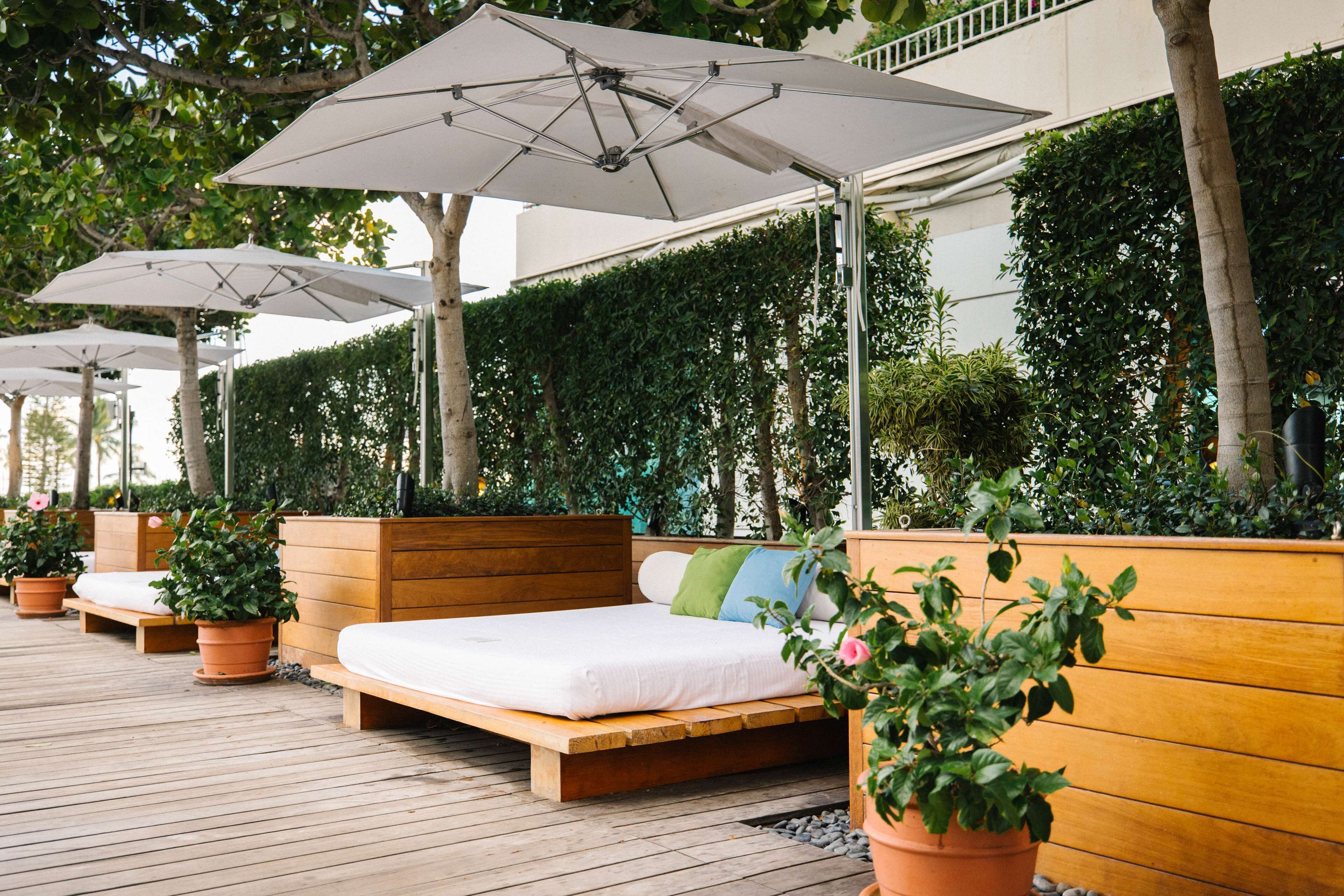 A wooden deck with outdoor seating and umbrellas, surrounded by lush greenery.
