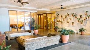 A spacious lobby with wicker sofas, a coffee table, and a reception desk. - Hilton Vacation Club The Modern Honolulu (Honolulu)