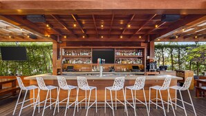 A bar area with a wooden ceiling, bar stools, and a variety of bottles. - Hilton Vacation Club The Modern Honolulu (Honolulu)