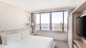 Een hotelkamer met een groot bed, een televisie en een raam met uitzicht op de stad.