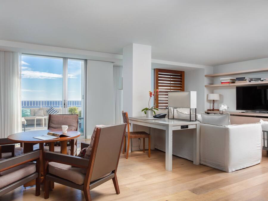 Et moderne hotelværelse med spiseplads, opholdsstue med TV og balkon med udsigt.
