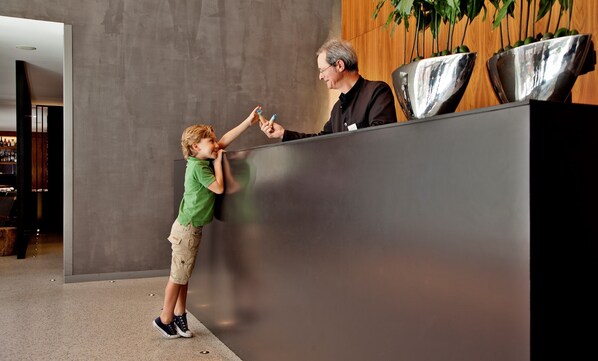 A reception area with a modern design, featuring a large reception desk and a wooden panel wall.