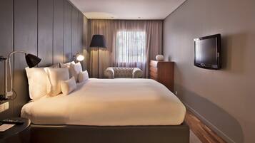 Een moderne hotelkamer met een groot bed, een bureau met lamp, een televisie en uitzicht op de omgeving.