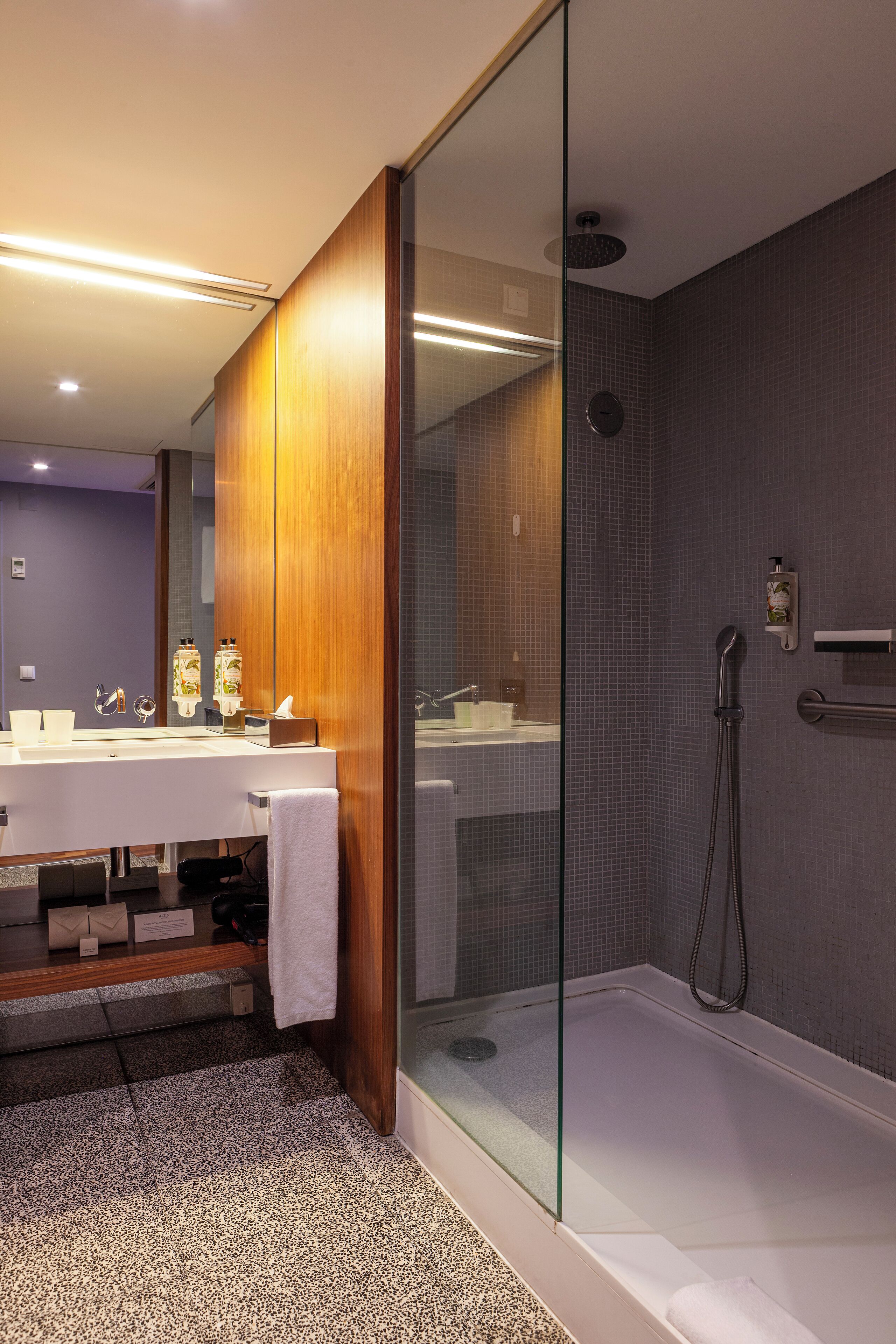 A modern bathroom with a glass-enclosed shower, a double sink vanity, and a visible towel rack.