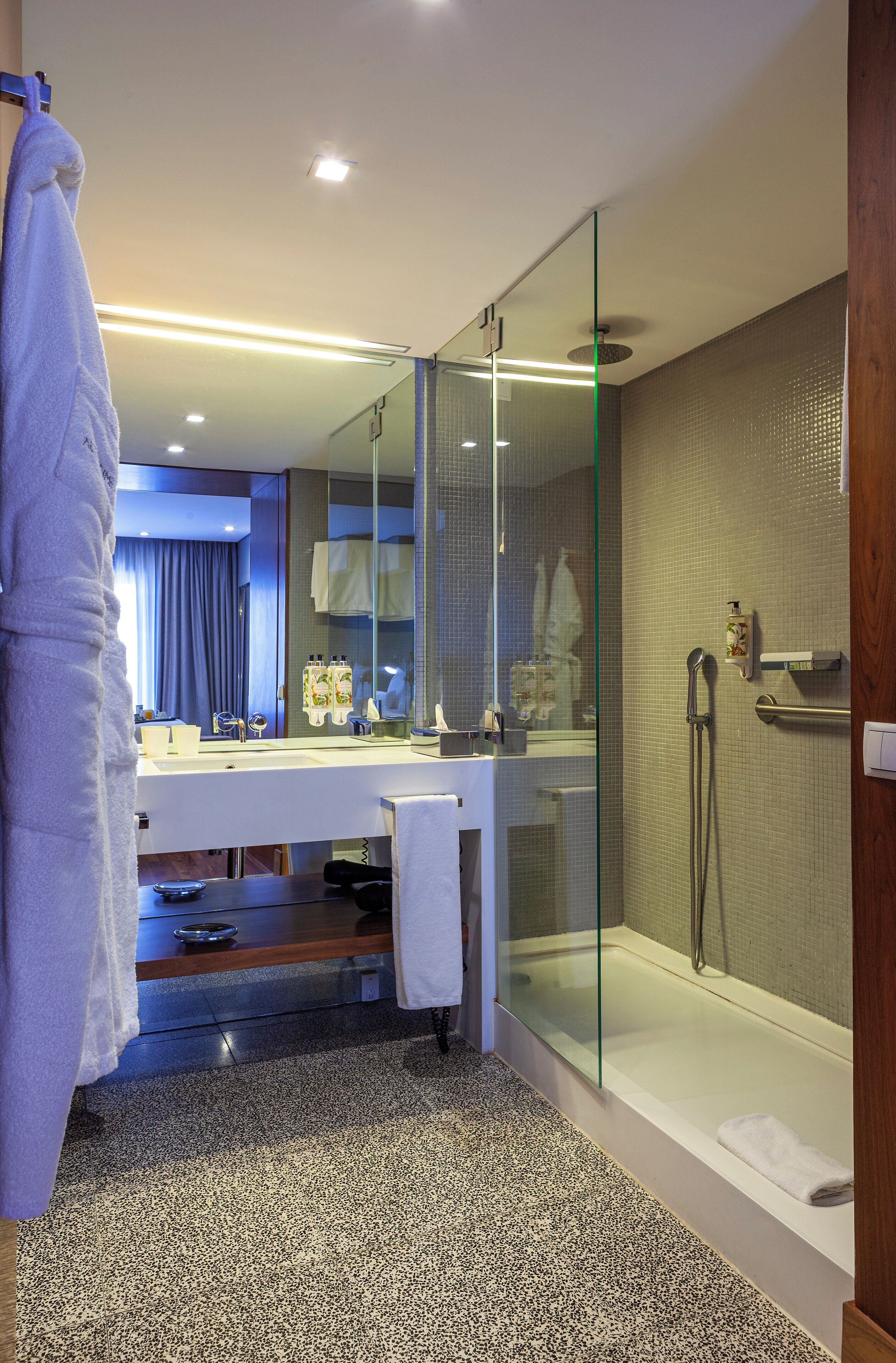 A modern bathroom with a glass-enclosed shower, a white sink, and a large mirror.