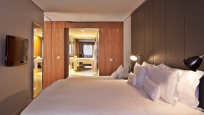 Une chambre d’hôtel avec un grand lit, un téléviseur fixé au mur et un miroir.