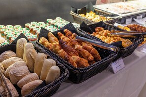 A variety of baked goods including bread and pastries displayed in baskets. - Altis Prime Hotel de Apartamentos (Lisbon)
