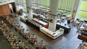 Un restaurant spacieux doté de plusieurs espaces de restauration, comprenant des tables et des chaises, ainsi qu’un bar central.