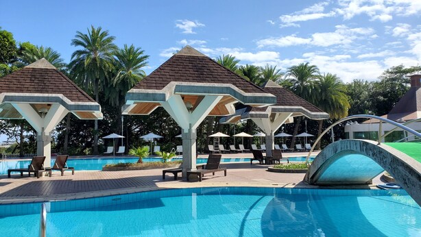 Un espace piscine aménagé avec des chaises longues, des parasols et une piscine à l’eau d’un bleu cristallin.