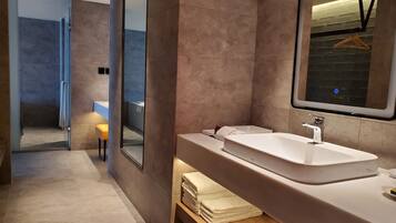 A modern bathroom with a large mirror, a white sink, and a wooden vanity.