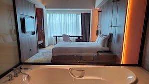 Une chambre d’hôtel avec une grande baignoire, un lit, un bureau et un téléviseur.