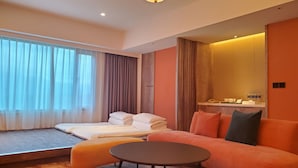 Une chambre d’hôtel moderne équipée d’un lit, d’un canapé, d’une petite table et d’une grande fenêtre avec des rideaux.