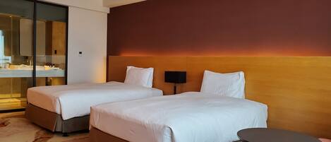 A hotel room with two beds, a small table, a sofa, and a large mirror.