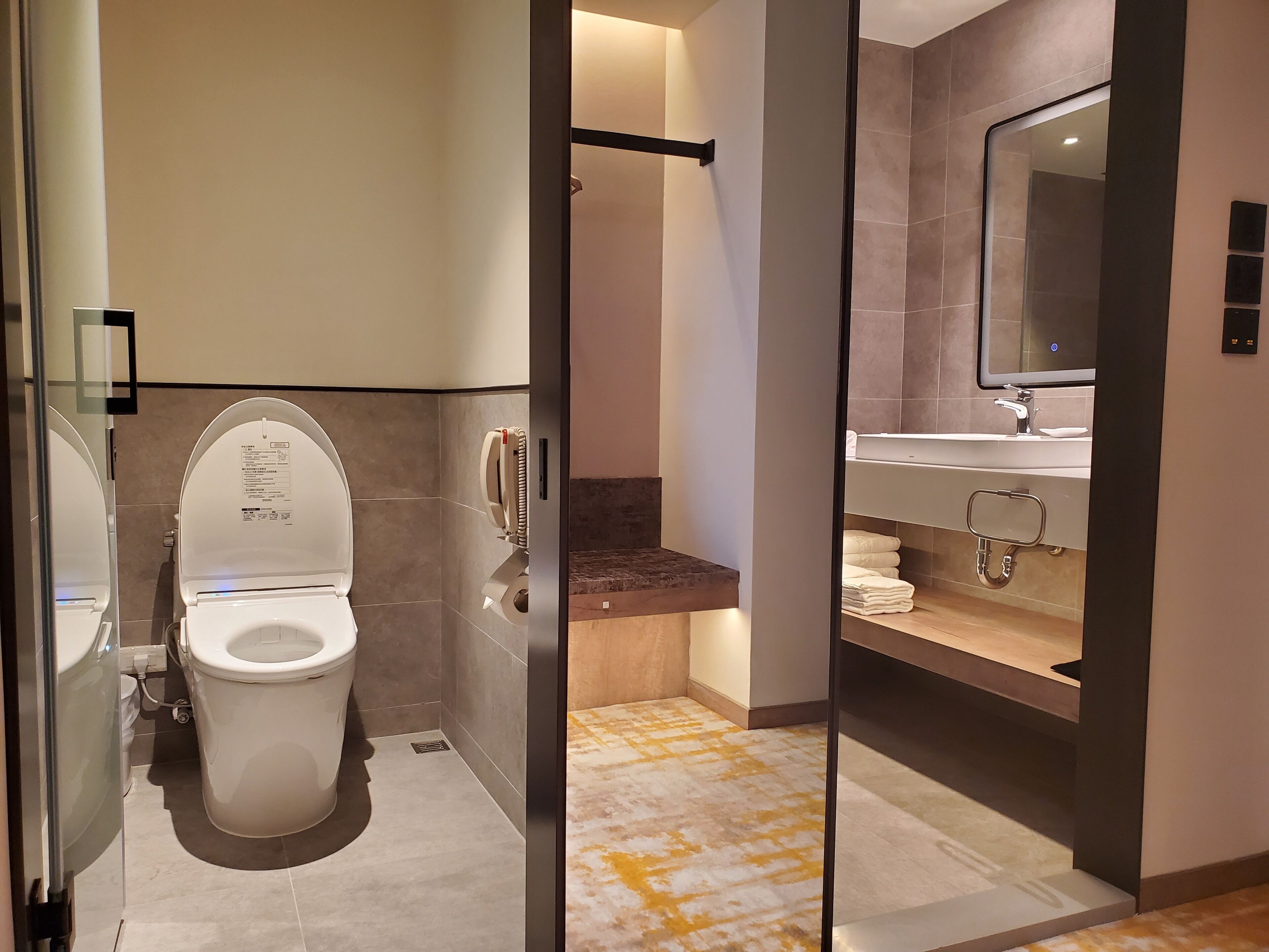 A modern bathroom with a toilet, a hand dryer, and a sink with a mirror.