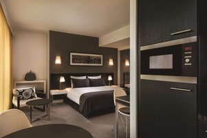 Ein modernes Hotelzimmer mit einem großen Bett, Nachttischen, einem Schreibtisch und einem Fernseher.