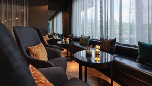 Ein modernes Wohnzimmer mit einer Couch, Sesseln und einem Couchtisch. Auf dem Tisch liegen Dekorationen und die Couch ist mit Kissen ausgestattet.