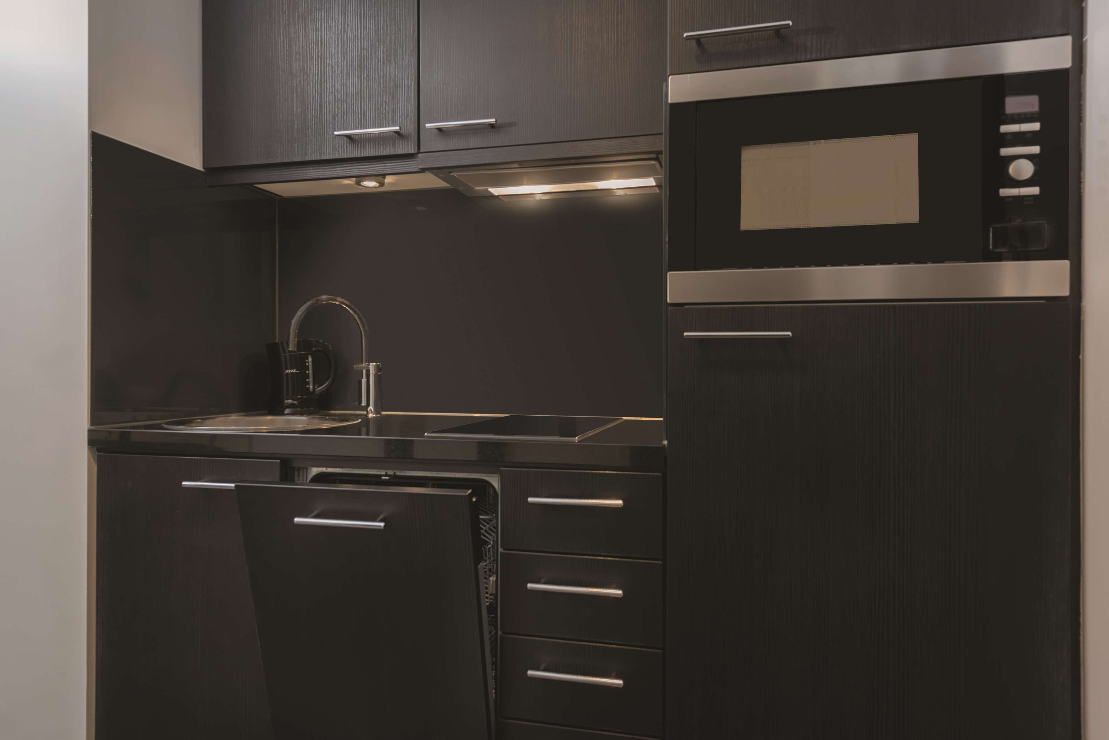 A modern kitchen with dark cabinetry, stainless steel appliances, and a built-in microwave.