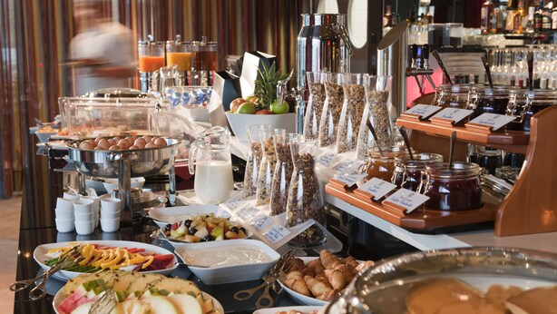Ein Buffet mit verschiedenen Speisen, darunter Obst, Gebäck und Getränke.