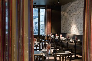 Ein modernes Restaurant mit gedeckten Tischen, einer Wand mit Muster und großen Fenstern.