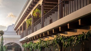 Une cour dotée d’un balcon abrité, d’une végétation luxuriante et d’un puits en pierre.