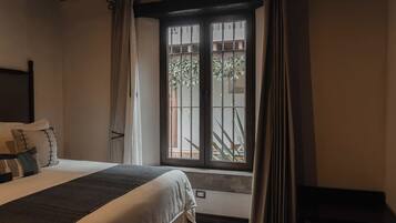 Una habitación de hotel con una cama, una ventana con cortinas y vistas a zonas verdes, además de una mesita.
