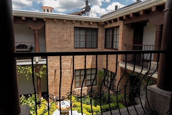 A brick building with a balcony, a staircase, and a garden.
