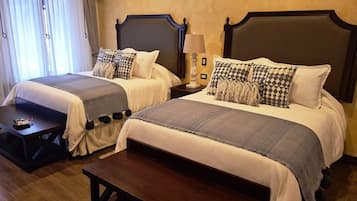Una cama doble con cabecera, mesita de noche y lámpara.